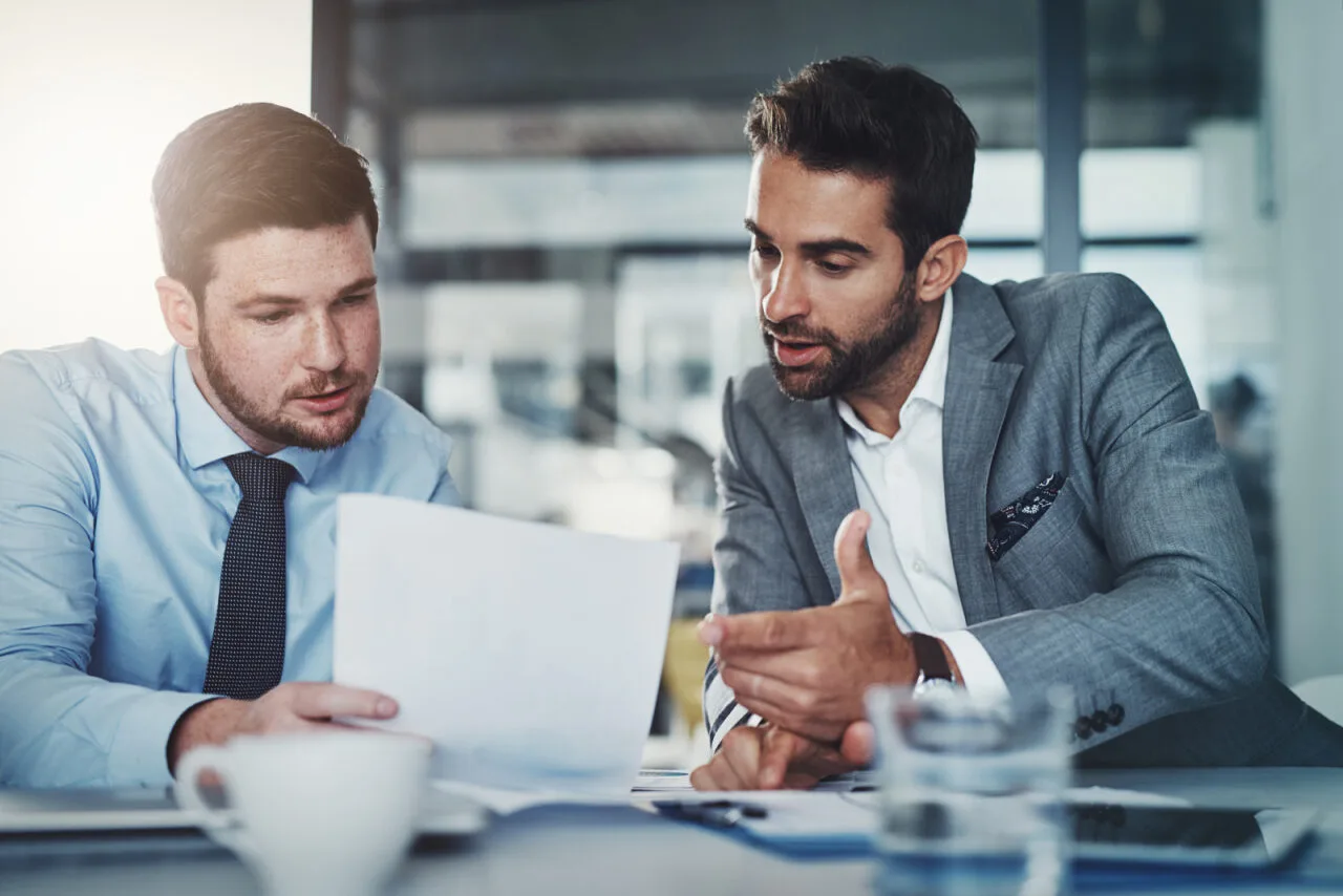 Dos hombres de negocios hablando sobre unos documentos que están mirando