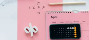plano detalle de un calendario rosa y una calculadora